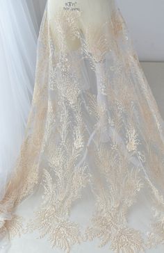 a wedding dress on display in front of a white wall with sheer fabric covering it