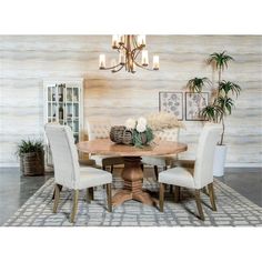 a dining room table with four chairs and a potted plant on the side wall