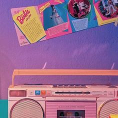 an old fashioned radio sitting on top of a table next to a wall with posters above it