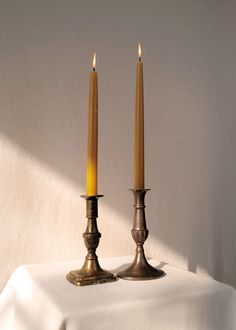 two candles sitting on top of a white table cloth