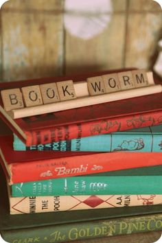 several books stacked on top of each other with scrabble blocks spelling the word book worm