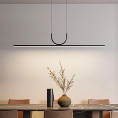 a dining room table with chairs and a vase on it's centerpiece in front of a white wall