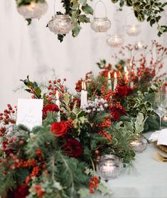 the table is set with candles, flowers and greenery for an elegant winter wedding