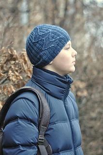 a person wearing a blue jacket and hat with a backpack in front of some trees