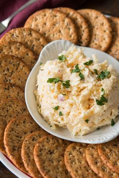 a white plate topped with crackers next to a bowl of mashed potato salad