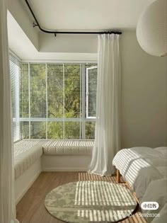 the sun shines through the window in this bedroom with white curtains and wood flooring