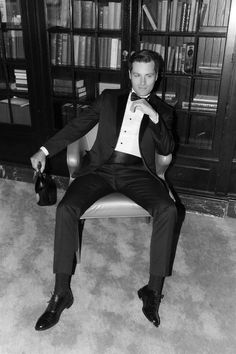 a man in a tuxedo sitting on a chair