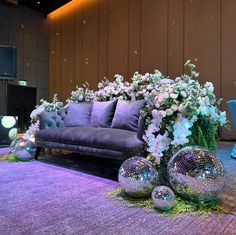 a living room filled with purple couches and flowers on top of carpeted flooring