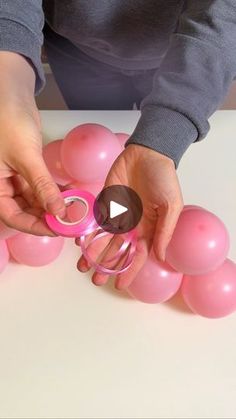 a person holding some pink balloons with scissors in their hands and making them look like they are floating