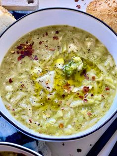 a bowl of broccoli soup with bread on the side