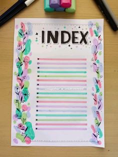 an index paper with flowers on it next to markers and pencils