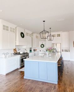 a large kitchen with white cabinets and wood flooring is pictured in this image, there are wreaths hanging from the ceiling