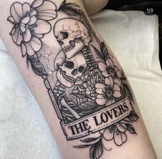 a black and white photo of a skull with flowers on it's leg that says the lovers