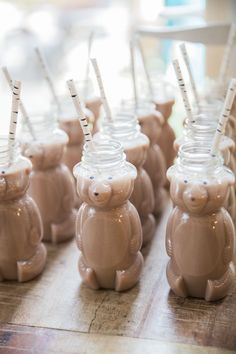 there are many little teddy bears in the cups on the table with straws sticking out of them