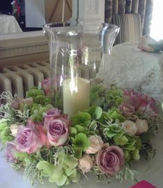 a vase filled with flowers sitting on top of a table next to a lit candle