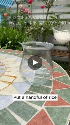 a glass vase sitting on top of a table next to a potted planter