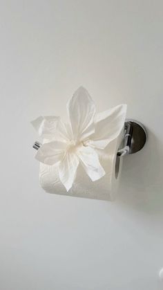 a toilet paper roll with a white flower on it is hanging from the side of a wall