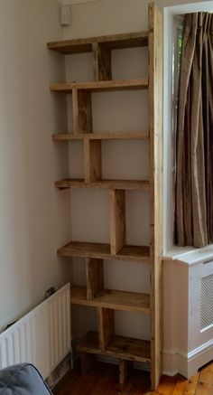 an empty room with wooden shelves in the corner and a radiator next to it