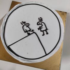 a cake decorated with two cartoon figures on top of white frosting and gold foil