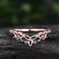 a rose gold ring with three diamonds on the side, sitting on top of a piece of wood