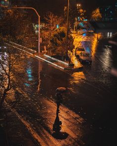 a person with an umbrella is walking down the street in the rain on a rainy night