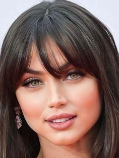 a close up of a person with long hair and green eyeshade wearing earrings