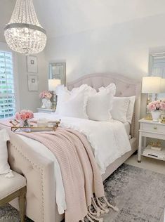 a bedroom with white furniture and pink flowers on the bed