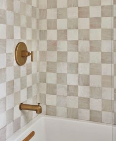 a bath tub sitting next to a wall with checkered tile on the walls and floor