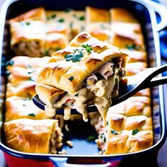 a person holding a spoon full of food in a casserole dish with meat and cheese on it