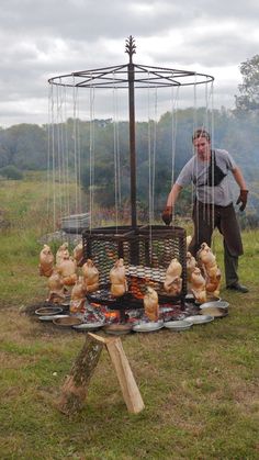 a man standing next to a grill filled with chickens