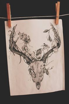 a drawing of a deer's skull with flowers on it hanging from a clothes line