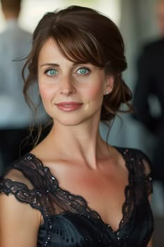 a woman in a black dress with blue eyes and brown hair smiling at the camera