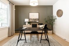 a room with a desk, chair and rug on the floor in front of a window