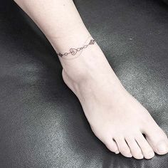 a woman's foot with a chain tattoo on the side of her left ankle