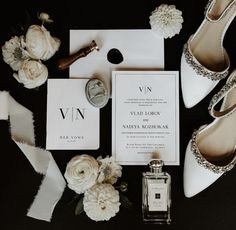 the wedding stationery is laid out with shoes, flowers and perfume bottle on it