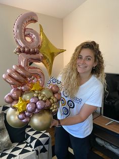 a woman standing next to a giant balloon number six in front of a tv set