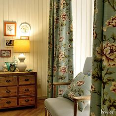 a chair sitting in front of a window next to a dresser with flowers on it