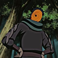 a man standing in front of trees with an orange spiral on his head and scarf around his neck