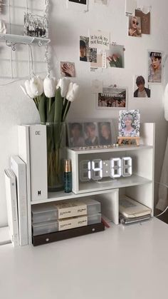 an alarm clock sitting on top of a white shelf next to a vase with flowers