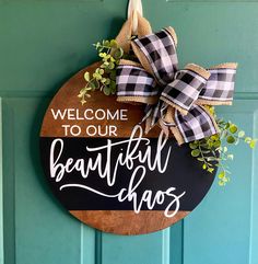 a welcome sign hanging on the front door with a bow around it that says, welcome to our beautiful chaos