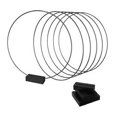 a set of four metal rings on top of each other next to a black box