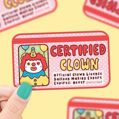 a person holding up a business card in front of some stickers that say certified clown