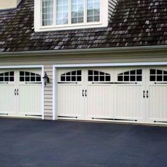 three white garage doors in front of a house