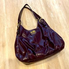 Good Condition Used Coach Patent Leather Hand Bag. Some Small Scuff Marks On The Bottom And Top Of Straps Depicted In Photos. Some Creasing From Use. Three Inside Compartments. Middle Compartment Is A Zip Closure, Two Outer Compartments Close Via Snap Each With Internal Pockets. Zippered Compartment Measures ~ 10” Wide And 6” Deep. Bottom Of Bag Measures 13” Wide. Color Is Deep Plum. Coach Purple Evening Bag, Coach Purple Shoulder Bag With Top Carry Handle, Coach Purple Bag With Adjustable Strap, Coach Purses Purple, Coach Purple Bags For On-the-go, Blue Coach, Coach Crossbody Purse, Tan Handbags, Buckle Bags