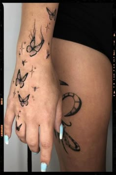 a woman's hand with tattoos on it and butterflies in the air above her