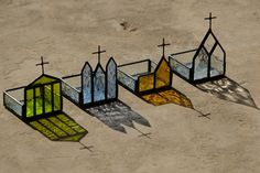 four stained glass windows with crosses on them sitting in the middle of a sandy area