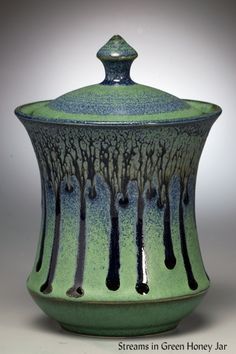 a green and blue vase with drips on it