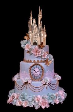 a three tiered cake decorated with flowers and a clock on the top, in front of a castle