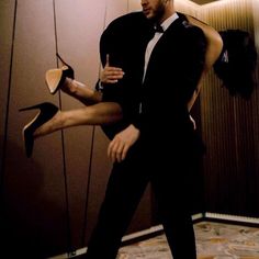 a man in a tuxedo is dancing with his legs up