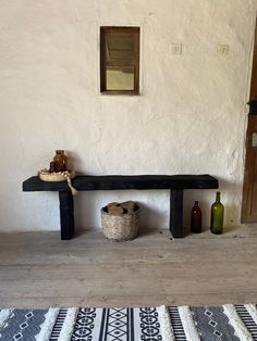 a wooden bench sitting on top of a floor next to a basket and bottle opener